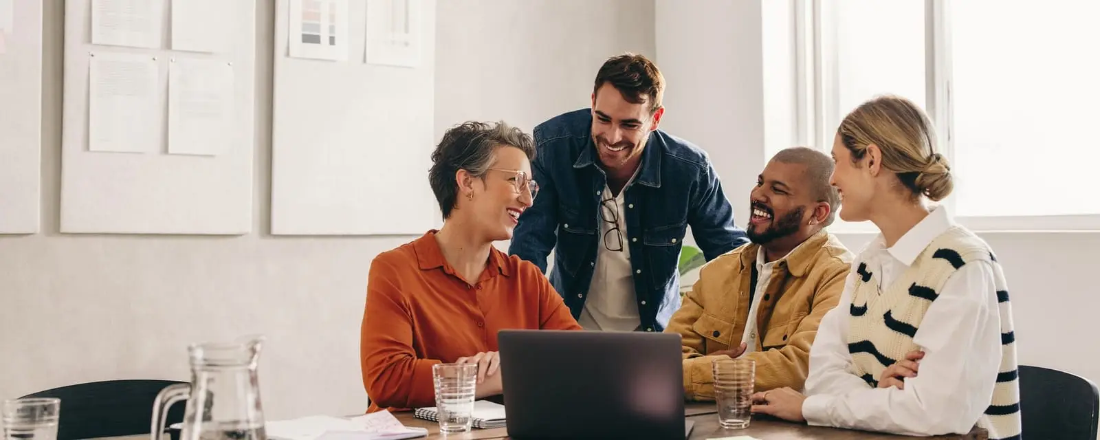 Coworkers laughing in front of a laptop in a casual office setting